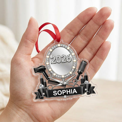 Clear acrylic ornament with a lit vanity mirror and salon tools, featuring SOPHIA and 2026 on a black banner.