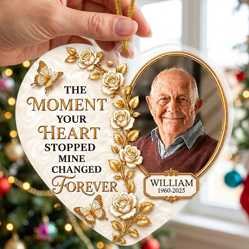 Heart-shaped acrylic ornament with a photo in a gold oval frame, white roses, gold butterflies, and a name plaque.