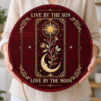 Round wooden sign with tarot-style sun and sleeping moon, floral vine, stars, and the words Live by the Sun, Love by the