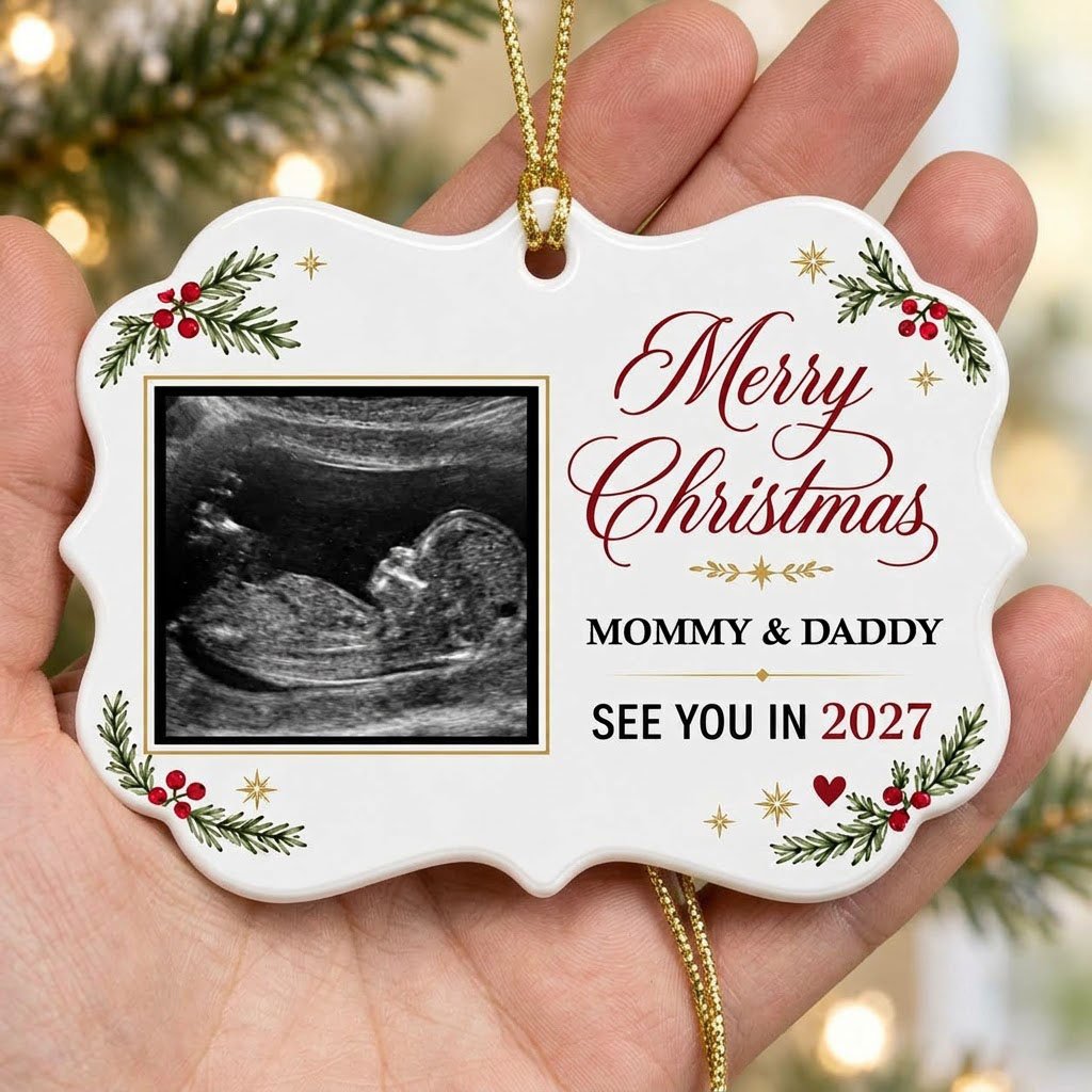 Round ceramic ornament with ultrasound photo, pine branches with red berries, gold starbursts and a red heart icon.