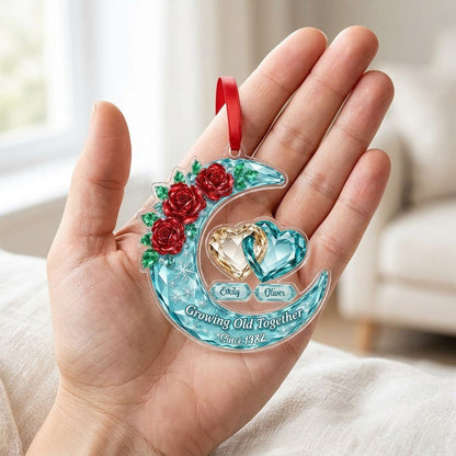 Custom-cut acrylic ornament of a faceted crescent moon with red roses, snowflakes, and two intertwined crystal hearts.