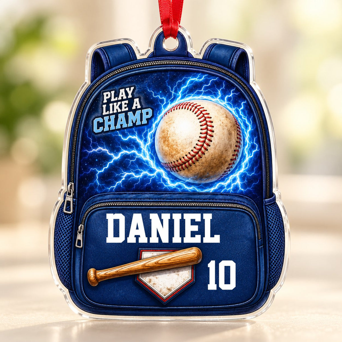 Backpack-shaped acrylic ornament with a baseball, blue lightning, a bat on home plate, and PLAY LIKE A CHAMP text.