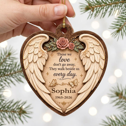 Heart-shaped wood ornament with angel wings, pink roses, butterflies, and a memorial quote with name and dates.