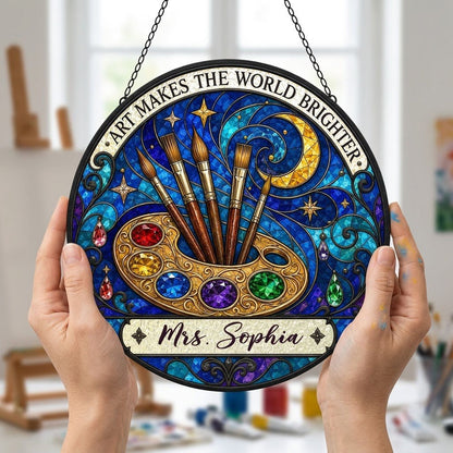 Round stained-glass suncatcher with golden palette, five brushes, moon, and 'Art Makes the World Brighter'.