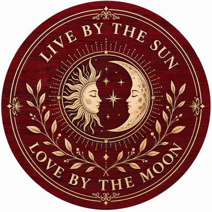 Round wooden sign with sun and crescent moon faces, stars, vines, and the quote Live by the Sun, Love by the Moon.