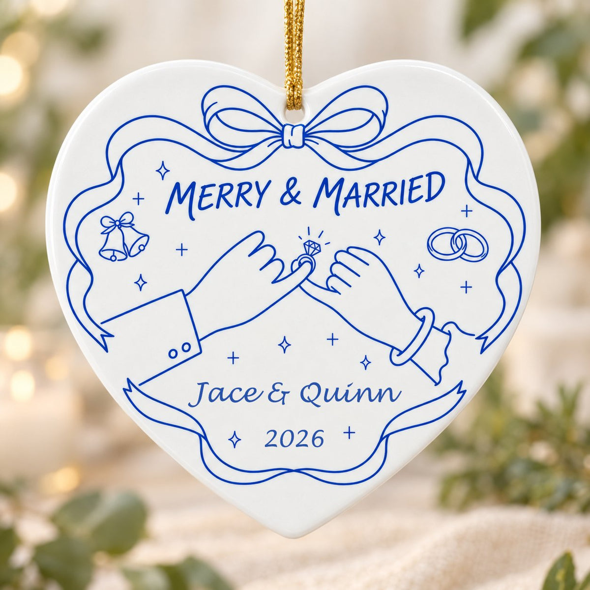 White heart ceramic ornament with blue line art: pinky promise hands, bells, rings, and MERRY & MARRIED text.