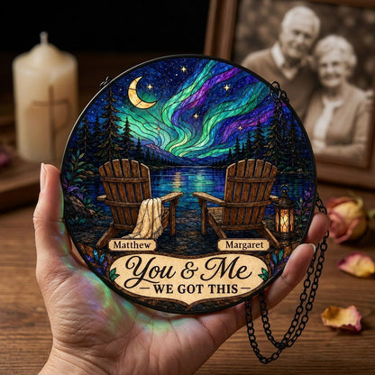 Round stained-glass style suncatcher with aurora, crescent moon, pine trees, lake, two chairs and a lantern.