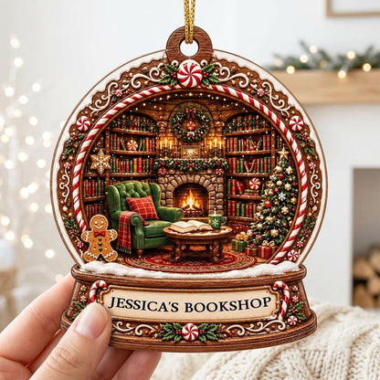 Snow globe ornament with candy-cane frame, cozy book-filled library, fireplace, tree, and 'JESSICA'S BOOKSHOP' nameplate