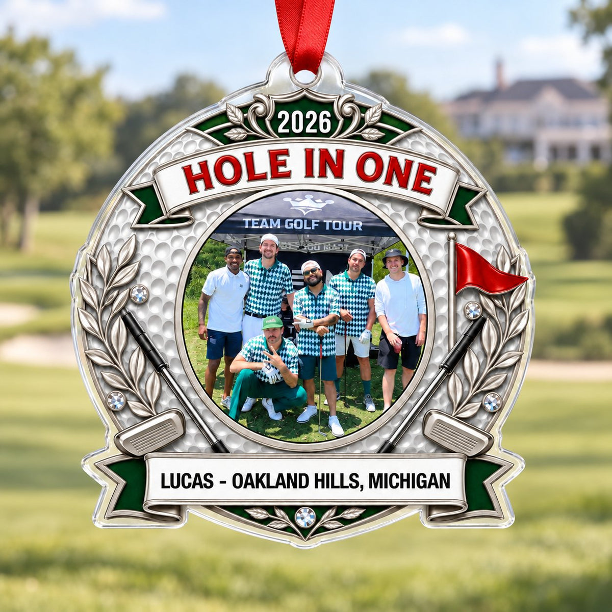 Silver trophy-style golf ornament with laurel branches, crossed clubs, red flag, 2026 and HOLE IN ONE, plus a circular p