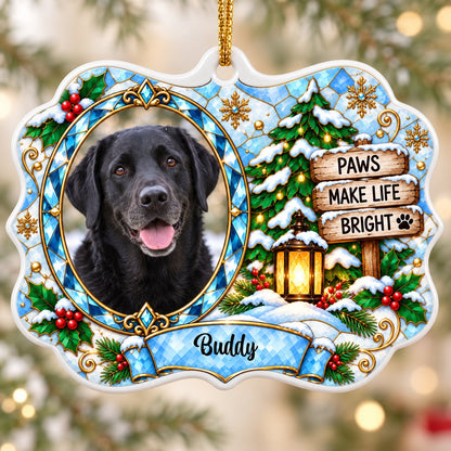 Scalloped ceramic medallion ornament with dog photo, blue stained glass frame, lantern, and Christmas tree in snow.