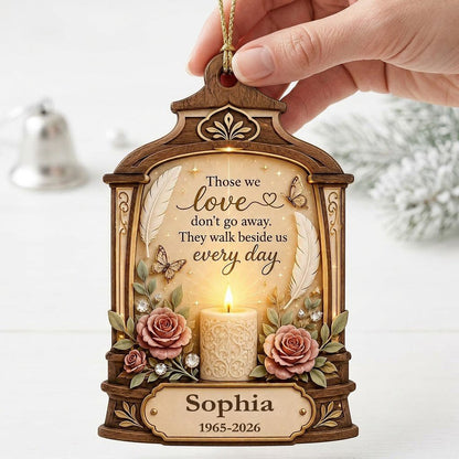 Arched wood-look ornament with lit white candle, two pink roses, butterflies, feathers, and a memorial quote.