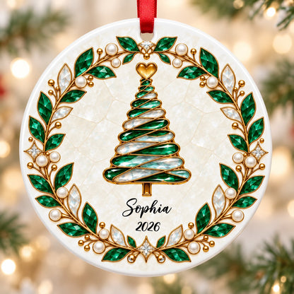 Round ceramic ornament with an emerald jeweled spiral Christmas tree and gold filigree wreath on cream.