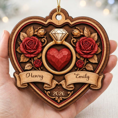 Heart-shaped wood ornament with a gold ring, red heart, red roses, and names Henry and Emily with year 2026.