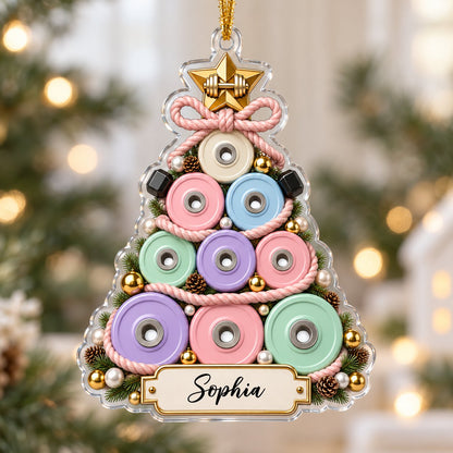 Acrylic Christmas tree ornament of stacked pastel weight plates with a gold star dumbbell and a cream name banner.
