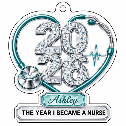 Clear acrylic ornament with a teal stethoscope heart, diamond 2026 numerals, teal ECG wave, and a personalized name bann