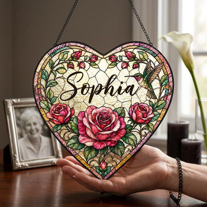 Heart stained-glass suncatcher with pink and red roses, a right-side hummingbird, and a multi-colored border.
