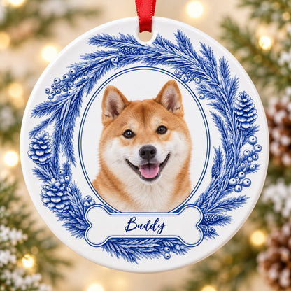 Round ceramic ornament with blue pine wreath, oval dog photo frame, and a blue-outlined bone at the bottom.