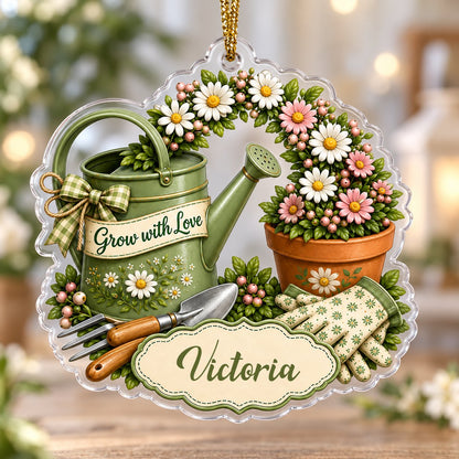 Green watering can with bow, garden tools, and floral pot with ‘Grow with Love’ and a name on a clear acrylic ornament.