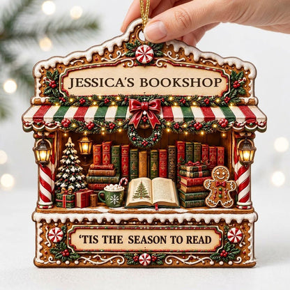 Gingerbread bookstore facade ornament with striped awning, wreath, books, lanterns, and 'TIS THE SEASON TO READ' text.