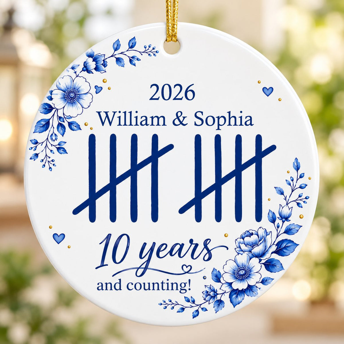 White round ceramic ornament with blue florals, tally marks, and 'years and counting!' plus names and year