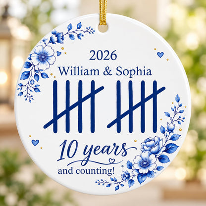 White round ceramic ornament with blue florals, tally marks, and 'years and counting!' plus names and year