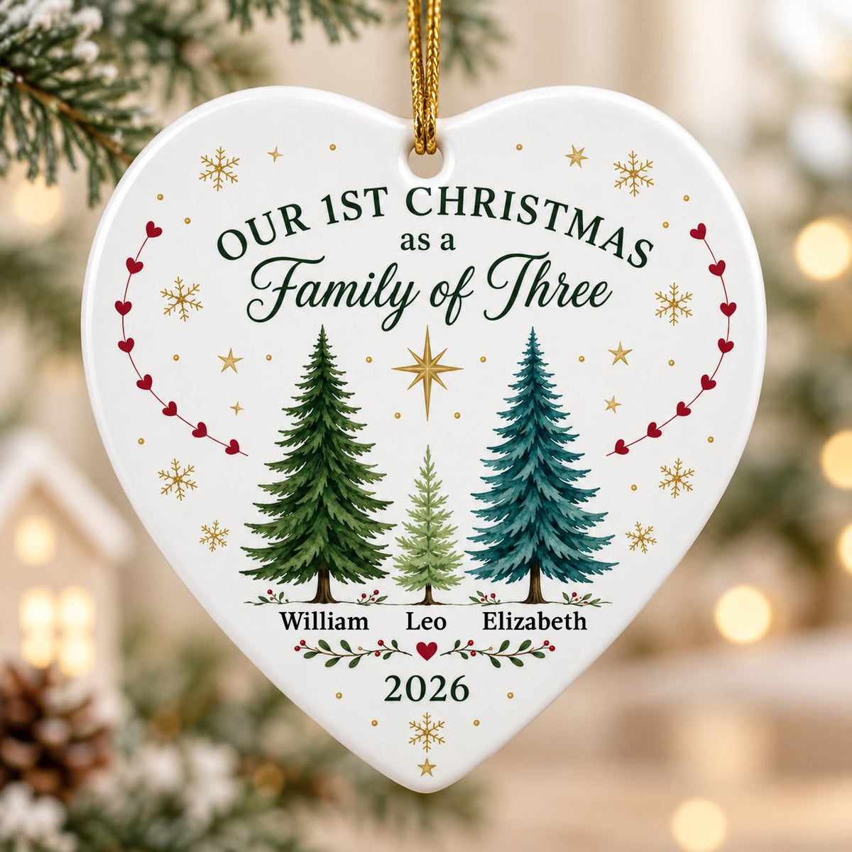 Heart ceramic ornament with three watercolor pine trees, a gold star, red heart garlands, and names with year.