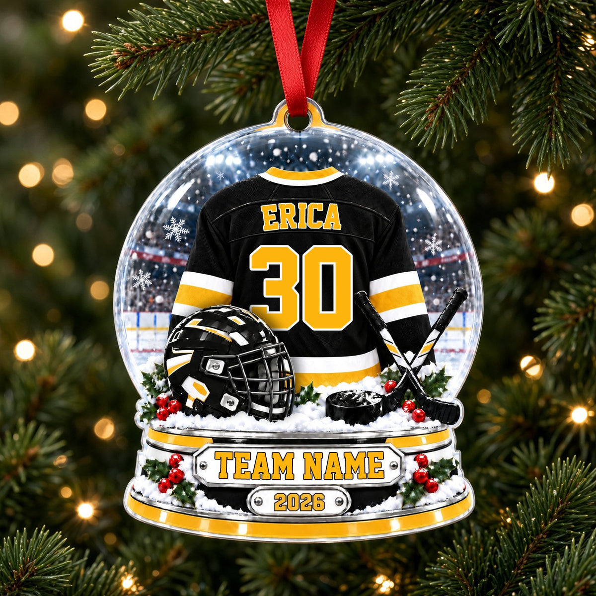 Snow globe acrylic ornament with black and gold hockey jersey, crossed sticks, puck, holly and a year plaque.