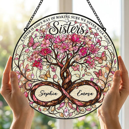 Round stained glass suncatcher with tree of life, pink blossoms, butterflies, and Sisters text with two names.