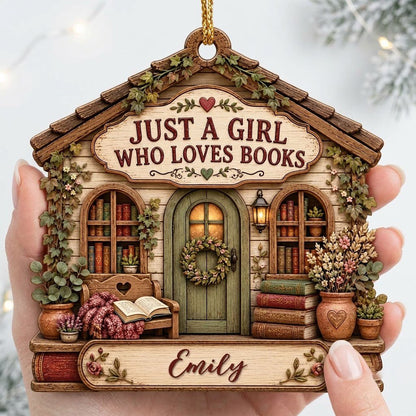 House-shaped wood ornament with 'JUST A GIRL WHO LOVES BOOKS', bookshelves, green door with wreath, and the name Emily.