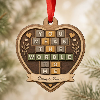 Heart-shaped wood ornament with Wordle-style tiles reading You Mean The Wordle To Me and names on a bottom banner.