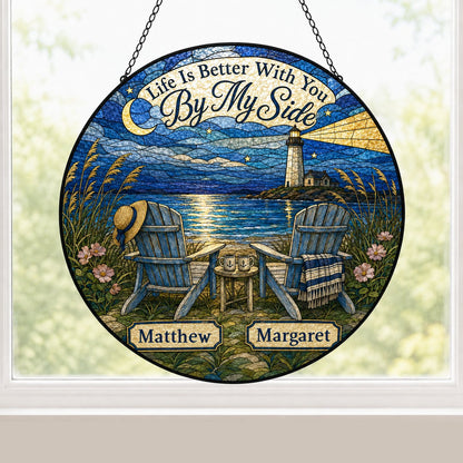 Round stained glass–style suncatcher with two blue Adirondack chairs by water and a lighthouse at night.