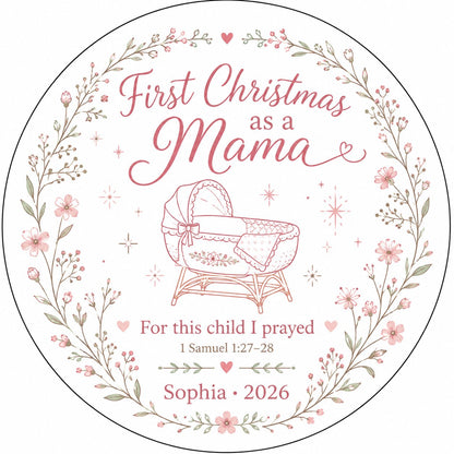 Round ceramic ornament with pink floral wreath, baby bassinet line art, stars, and First Christmas as a Mama.