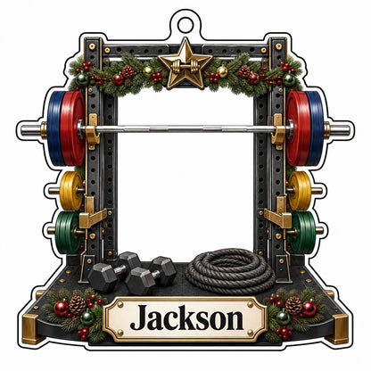 A squat rack-shaped acrylic ornament with garland, barbell, dumbbells, and a photo cutout above a name plaque.