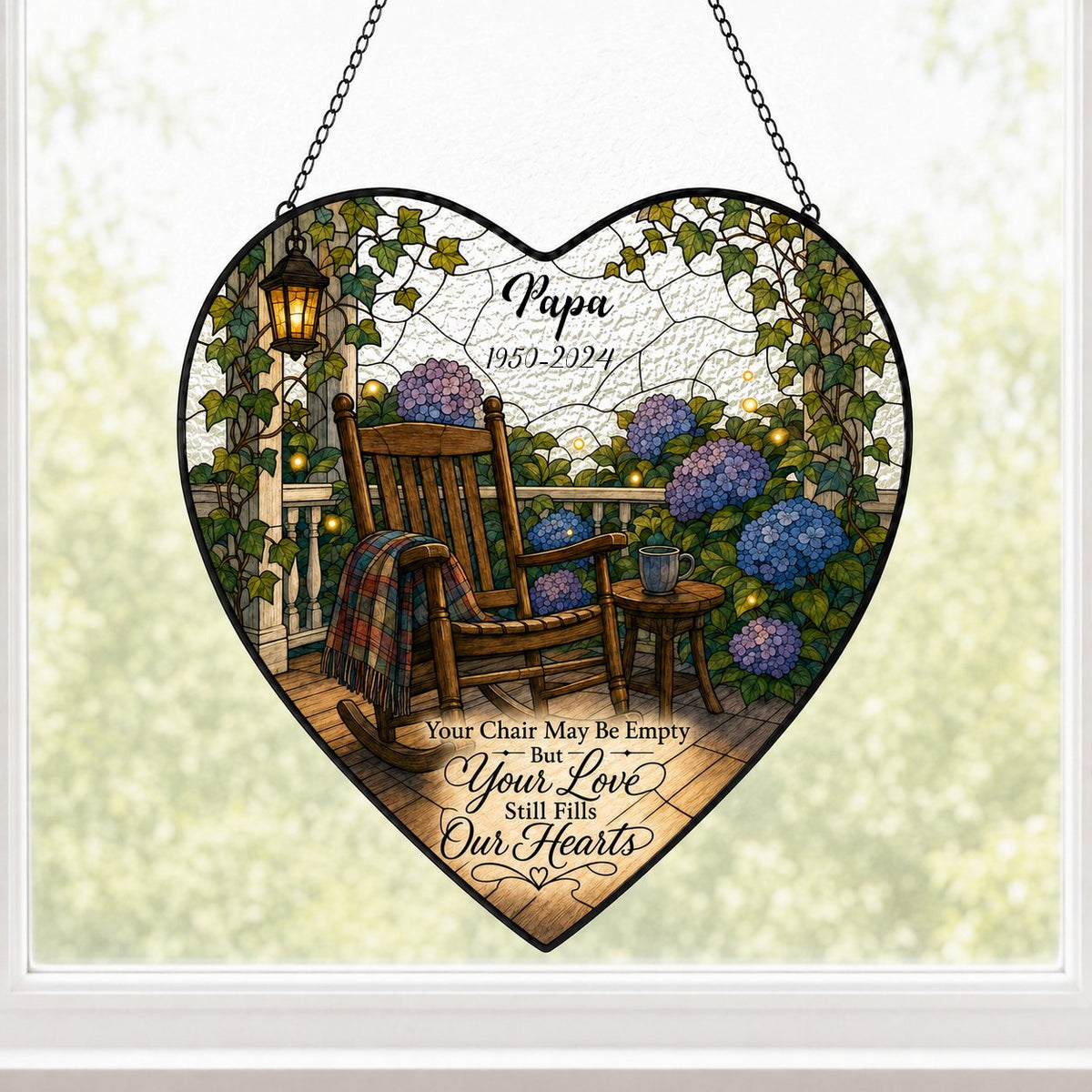 Heart stained glass suncatcher with empty porch rocking chair, lantern, ivy, and purple and blue hydrangea bushes.