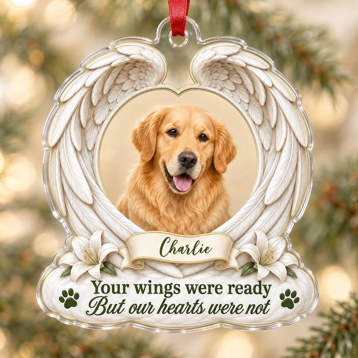 Clear acrylic angel wings ornament with a circular dog photo, white lilies, a dark green paw print, and a name banner.