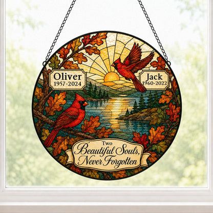 Two red cardinals with a glowing sun over a mountain lake and pine trees, framed by autumn oak leaves on a round suncatc