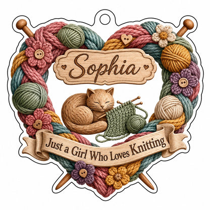 Heart-shaped acrylic ornament with yarn wreath, knitting needles, brown cat and "Just a Girl Who Loves Knitting" text.