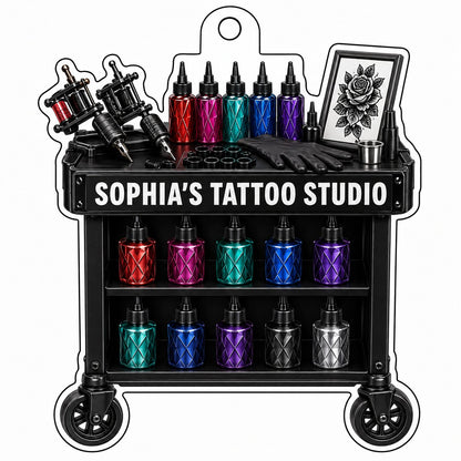 Acrylic ornament shaped like a tattoo cart with machines, colorful inks, and 'SOPHIA'S TATTOO STUDIO' text.
