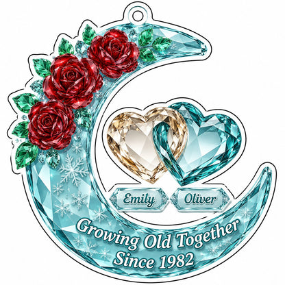Custom-cut acrylic ornament of a faceted crescent moon with red roses, snowflakes, and two intertwined crystal hearts.