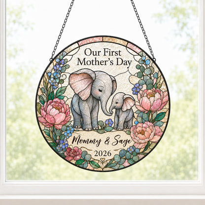 Round stained-glass suncatcher of mother and baby elephants touching trunks amid pink peonies and blue flowers.