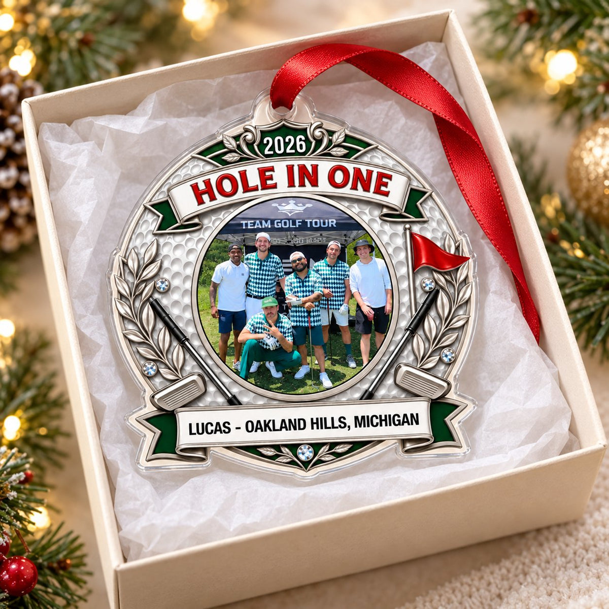 Silver trophy-style golf ornament with laurel branches, crossed clubs, red flag, 2026 and HOLE IN ONE, plus a circular p